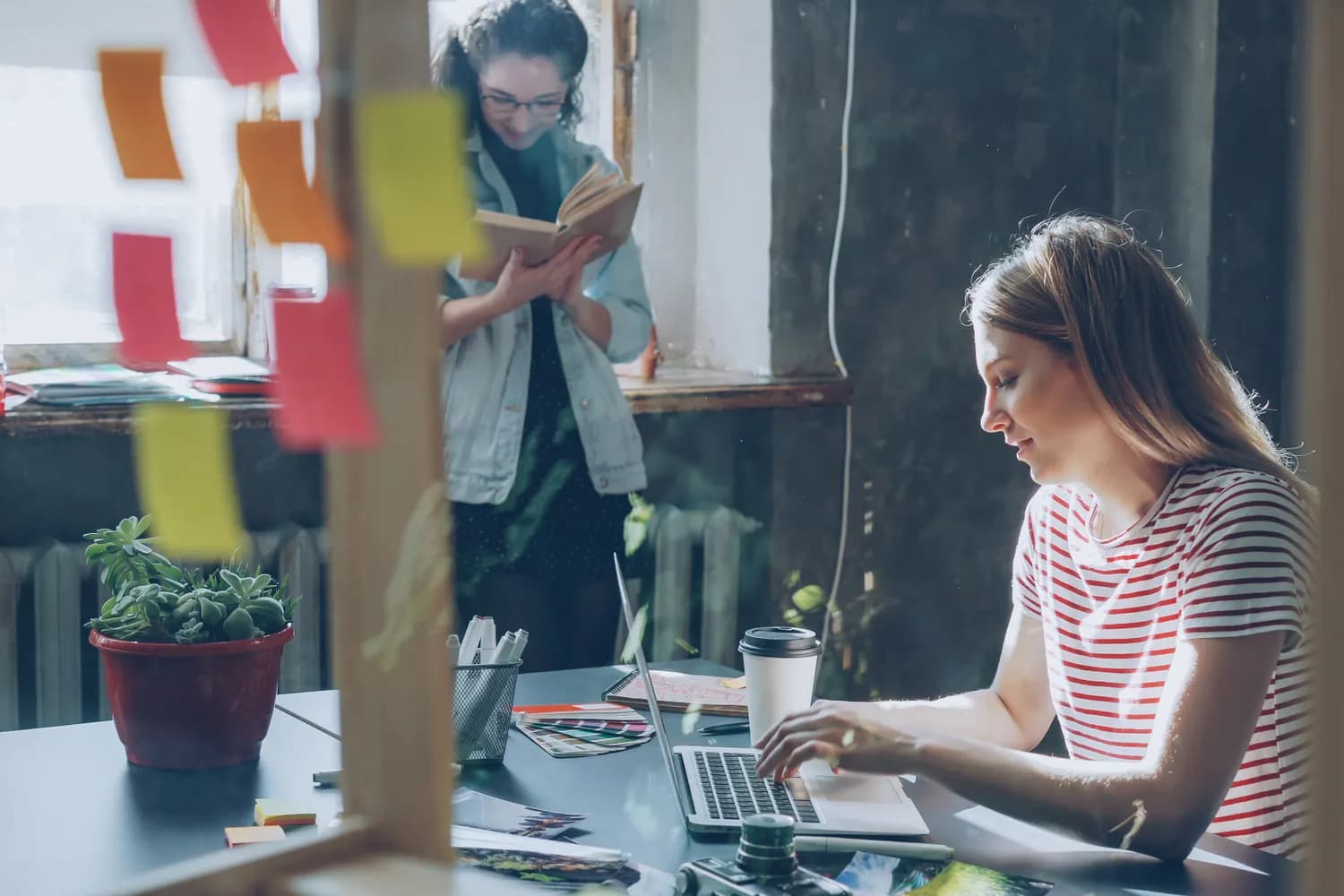 A focused professional working at a desk in a plant-filled studio
